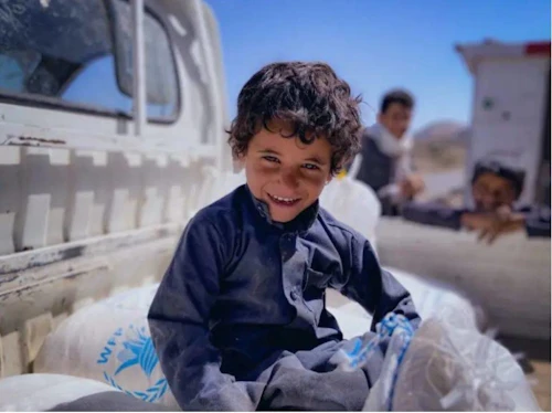 Omar, fjögurra ára, situr á hveitsekkjum WFP í Khawlan i Jemen. Mynd: WFP/Mohammed Awadh